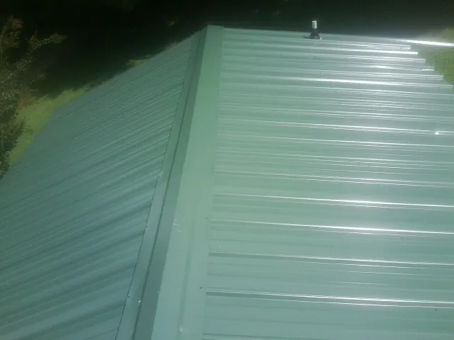 New green metal panels meeting at the ridge of a roof — Flat Roof Repair work by our crew in Glen Ridge