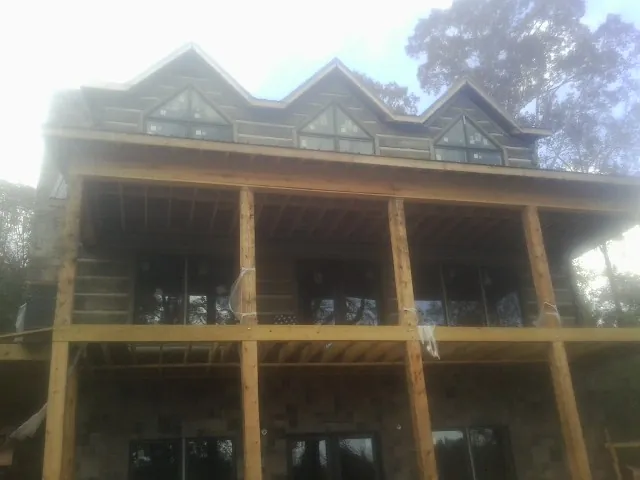Dormers and porch framing on a large log home under construction — Roof Coating work by our crew in Glen Ridge