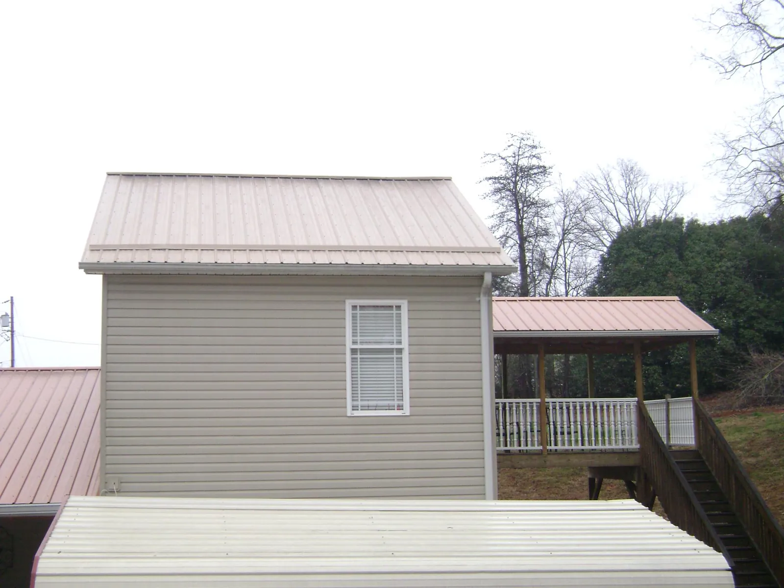 Tan metal roofs on a two story addition and attached porch, from a Roof Replacement job in Glen Ridge