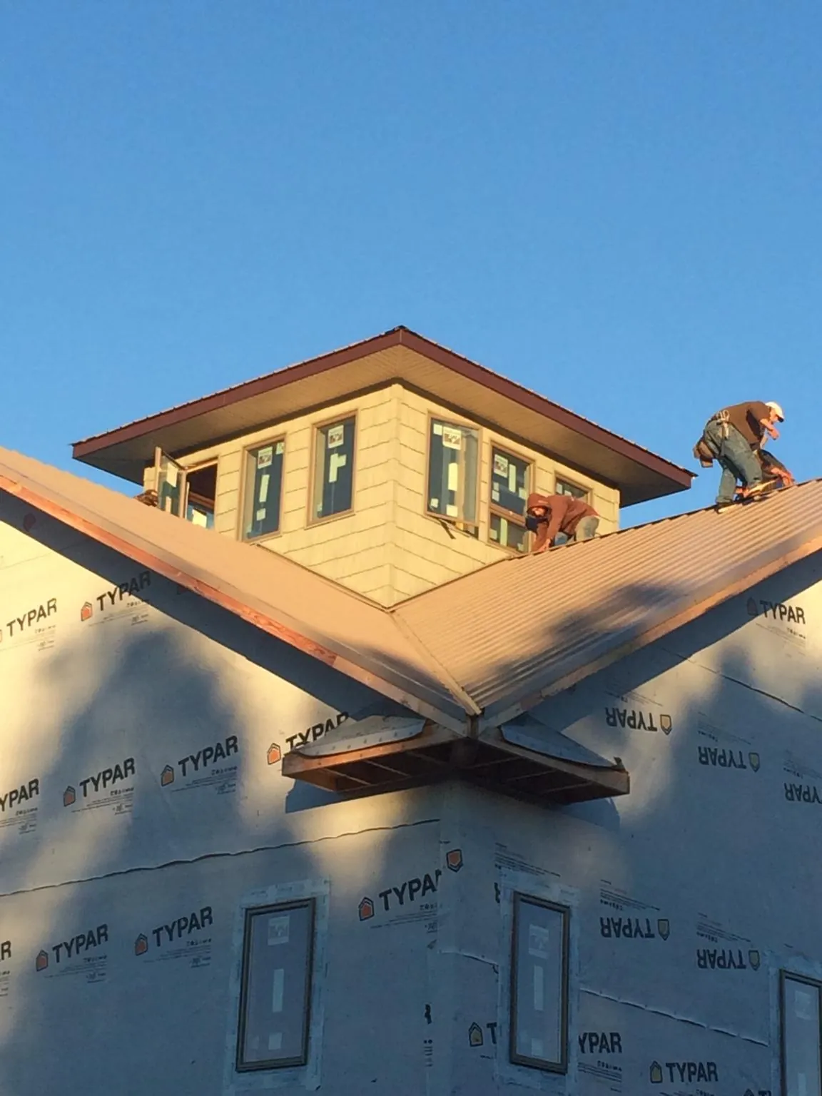 Roofers working around a rooftop cupola on a new metal roof at sunset — Roof Waterproofing in Glen Ridge by Roofing Brothers
